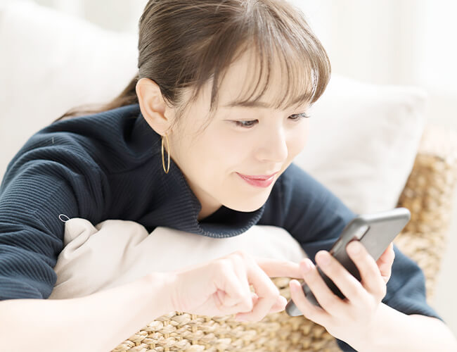 スマホでWEB予約を行う女性